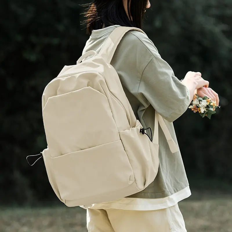 Person wearing a beige backpack with a blurred natural background
