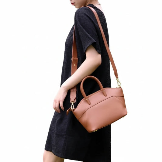 Person holding a brown handbag against a white background