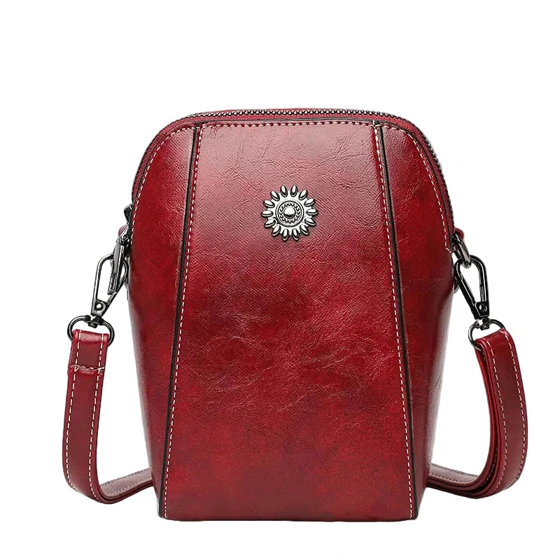 Red leather handbag with a decorative emblem on a white background