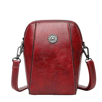 Red leather handbag with a decorative emblem on a white background