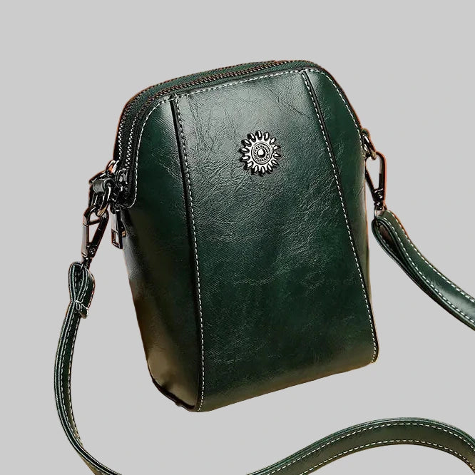 Green leather crossbody bag with a decorative clasp on a white background