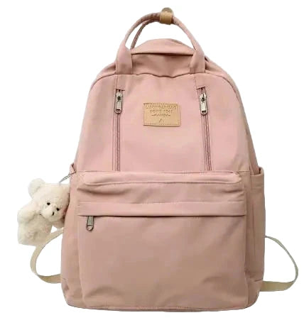 Pink backpack with a teddy bear attached on a gray background