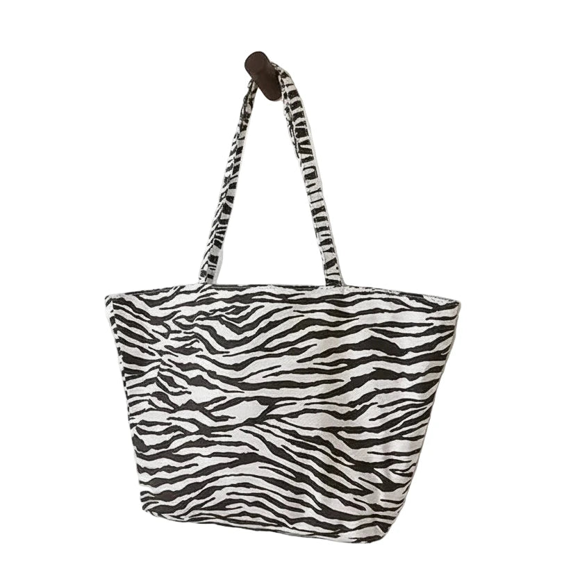Zebra print tote bag hanging on a hook against a white background