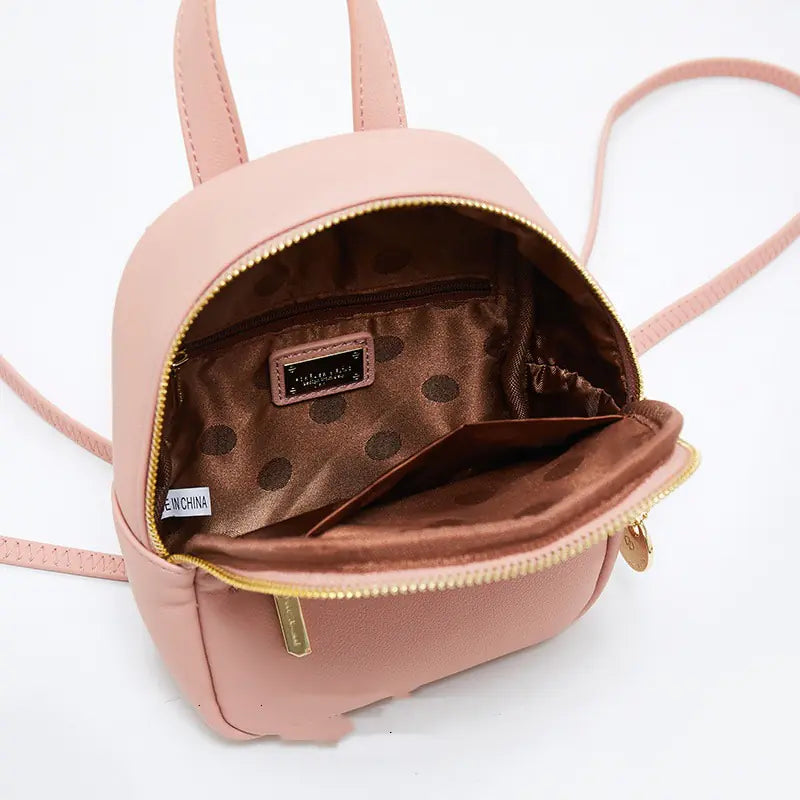 Pink backpack with open zipper showing polka dot interior on a white background